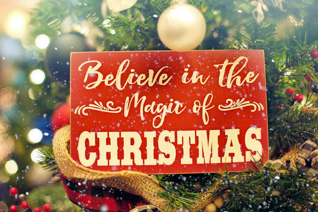 A vibrant Christmas sign amidst festive holiday ornaments, evoking the magic of the season.
